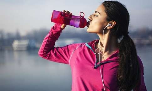Woman stopping to drink water while on a run